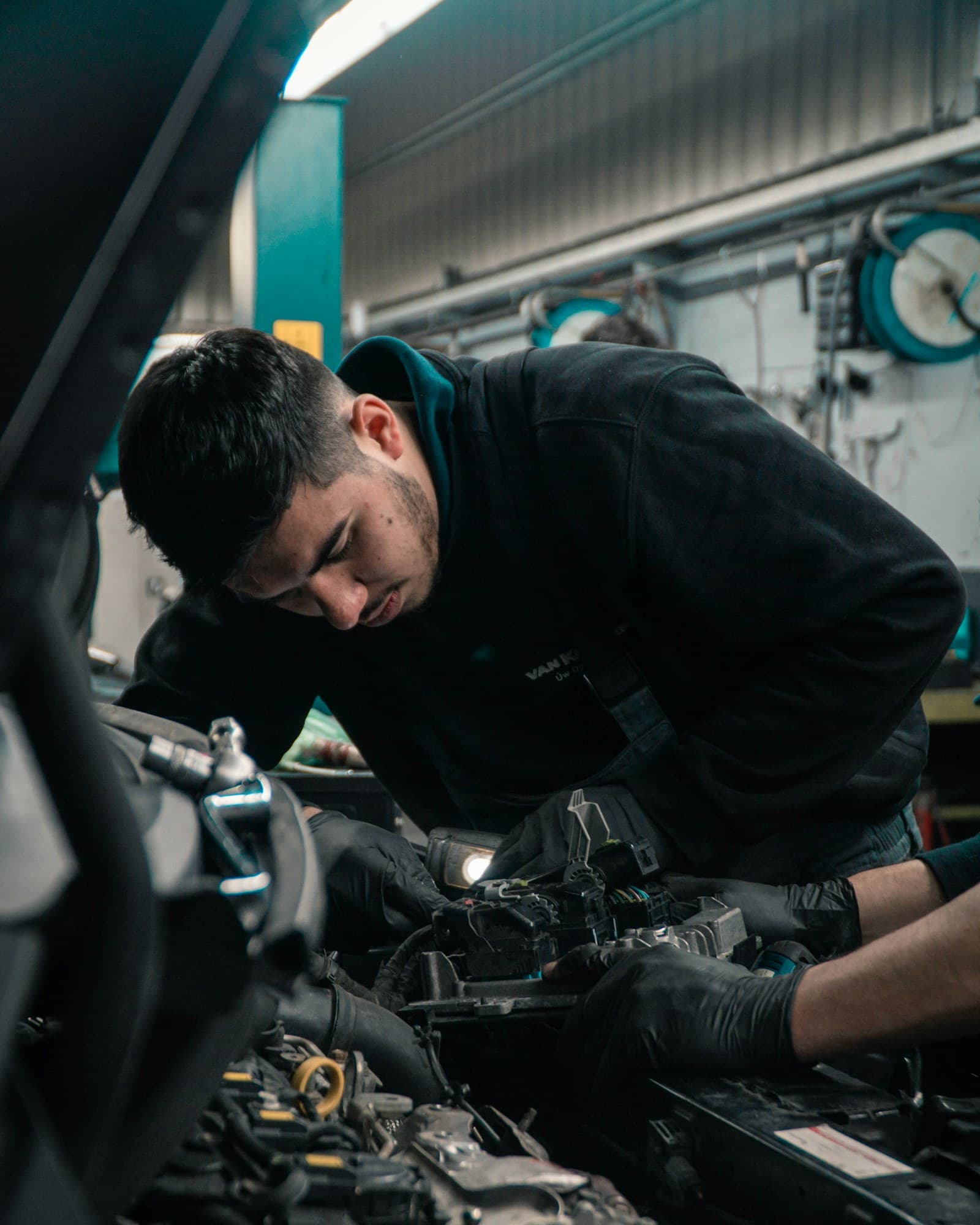 A technician working on an engine under workshop lighting
